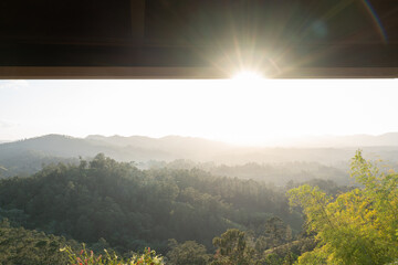 View of forested mountain landscape with misty atmosphere during sunset or sunrise