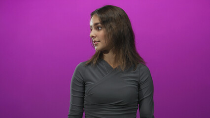 Fototapeta premium Young hispanic woman facing right showing her face and closed eyes in a studio with magenta purple backdrop; thoughtful.