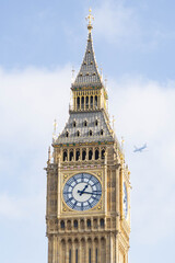 Die Spitze von Big Ben mit einem Flugzeug im Hintergrund