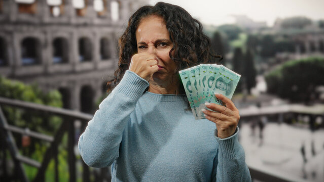 Fototapeta Woman in rome makes a disgusted face while holding chinese yuan banknotes in front of the roman coliseum, capturing a unique urban street scene in italy.
