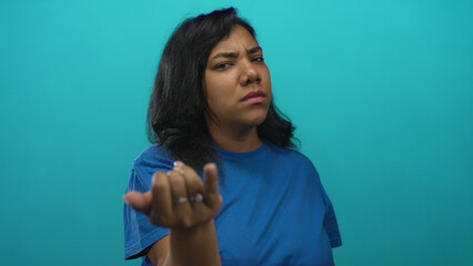 Woman wearing blue shirt with furrowed brow points finger to camera with direct gaze in studio; anger accusation.