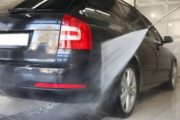 Washing auto with high pressure water jet at car wash, closeup