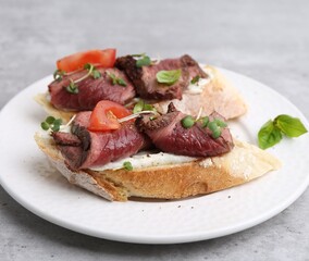 Delicious bruschettas with roast beef served on light table, closeup
