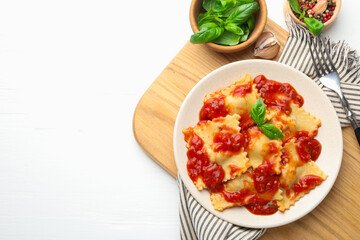 Delicious ravioli with tomato sauce and basil served on white wooden table, flat lay. Space for text