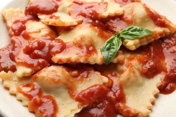 Delicious ravioli with tomato sauce and basil on plate, closeup