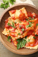 Delicious ravioli with tomato sauce and parsley on wooden table, top view