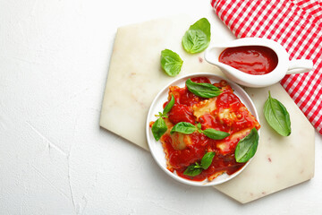 Delicious ravioli with tomato sauce and basil on white textured table, flat lay. Space for text