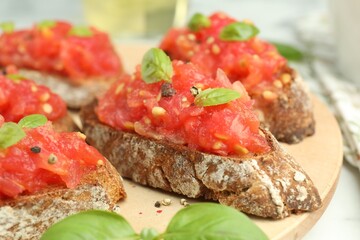 Tasty bruschettas with tomatoes and basil on white table, closeup
