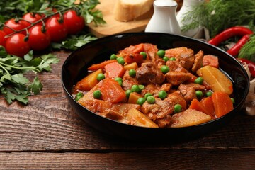 Delicious cooked stew and fresh ingredients on wooden table, closeup