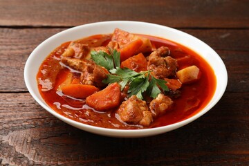 Delicious cooked stew in bowl on wooden table, closeup