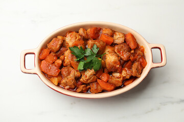 Delicious cooked stew in baking dish on white marble table, top view