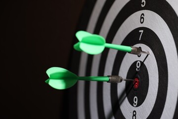 Dartboard with darts on black background, closeup