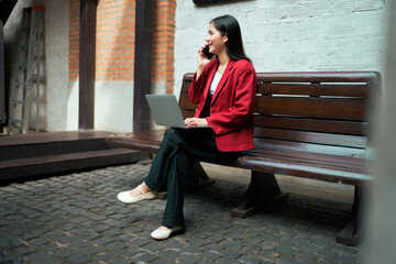 Businesswoman making phone call working on laptop outdoors