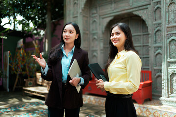 Asian businesswomen discussing work outdoors with laptop