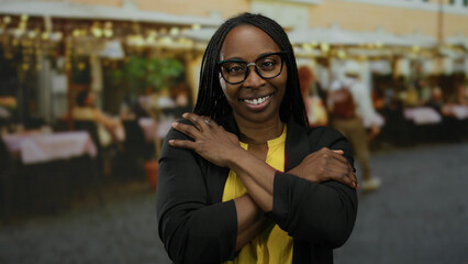 Fototapeta premium Woman smiling with arms crossed in a bustling outdoor market background, blending urban vibes with a warm expression, wearing glasses and a casual outfit