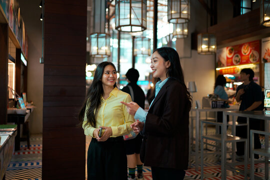 Asian women colleagues having a business conversation in food court