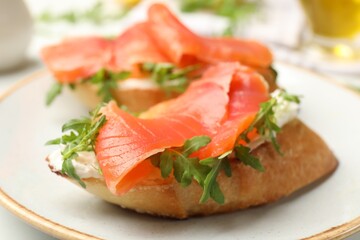 Tasty bruschettas with salmon and arugula served on table, closeup