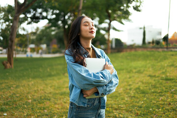 Young Asian woman student relaxing in park