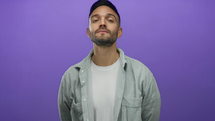 Young man with a confident expression poses against a vibrant purple background wearing a casual white shirt and striped jacket showcasing modern style and relaxed demeanor.