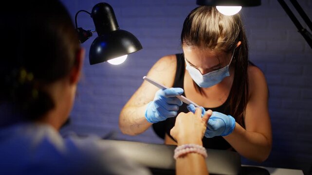 Professional manicurist performing nail care procedure creating elegant shape and smooth surface while taking care of beautiful hands in modern beauty salon. High quality 4k footage