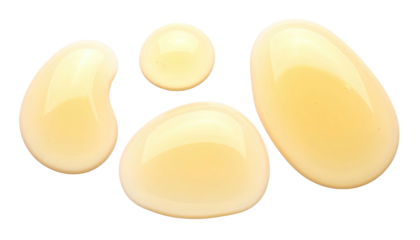 Droplets of golden liquid with reflective highlights against a stark black background