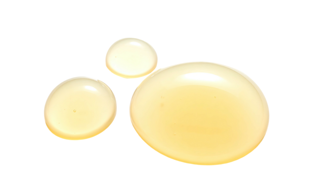 Three glistening, yellow droplets of liquid on a stark black background