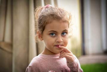 Portrait of a cute little girl with blue eyes wearing a pink sweater outdoors
