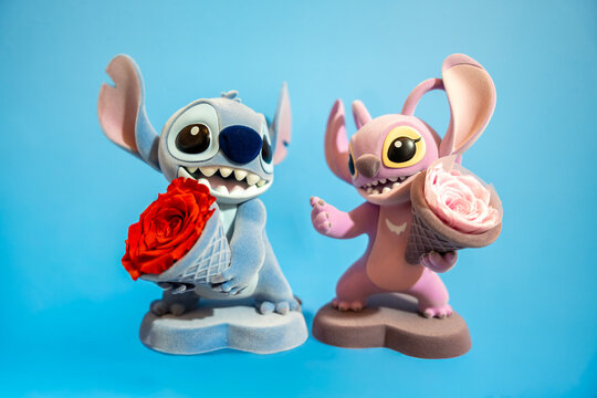 Bangkok, Thailand - July 1, 2025 : Cute couple blue and pink lilo stitch dolls hold bouquet of roses on blue background for valentine concept.