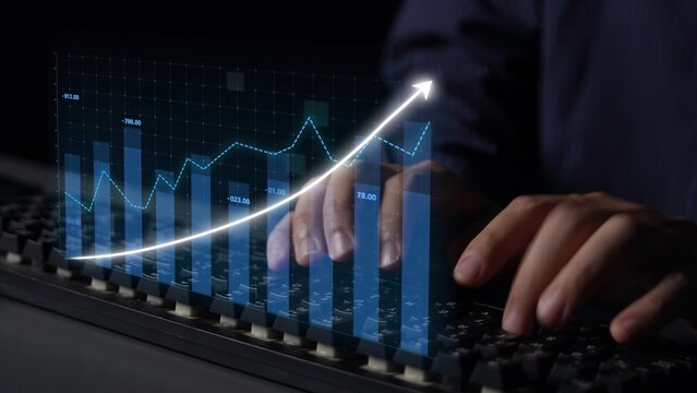 A close-up view of hands typing on a keyboard with a digital representation of graphs and data showcasing growth in finance and business analytics trends. Copula