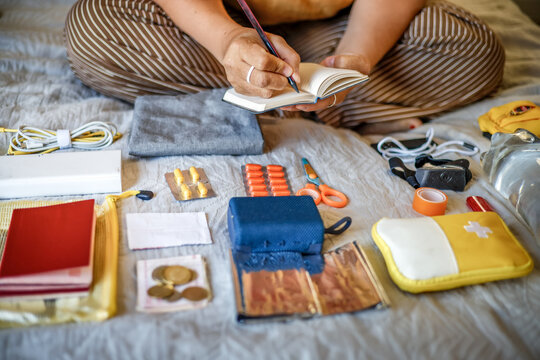 Emergency go-bag organization - middle-aged woman with notebook in bedroom