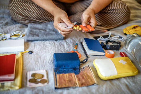 Emergency go-bag check - female hands folding necessary things in bedroom - Powered by Adobe