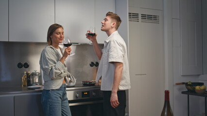 Love couple clinking goblets in modern kitchen. Smiling husband giving toast