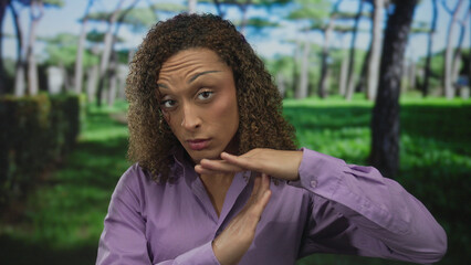 Woman holds hands in timeout gesture at lush green park under sunlight with tall pines and...