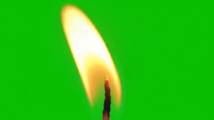 Closeup shot of a vibrant flickering candle flame on a dark wick isolated against a bright green screen background perfect for compositing and special effects.