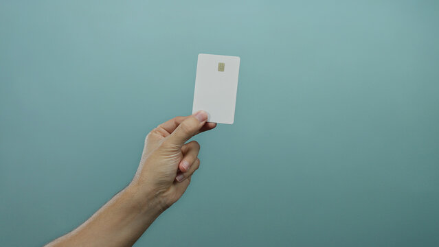 Man holding a credit card against a blue wall background, highlighting minimalistic style and secure payment concept. - Powered by Adobe
