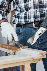 Carpenter using heat gun and wood scraper removes paint from old wooden window. Construction industry, carpentry. Restoration. 