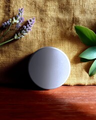 A cosmetic jar is placed on a wooden surface with lavender and green leaves on a golden fabric backdrop, suggesting natural beauty products.