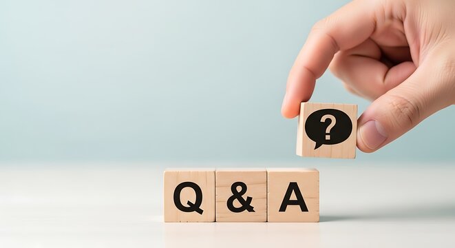 Hand placing a wooden block with a question mark and speech bubble icon on top of q a blocks