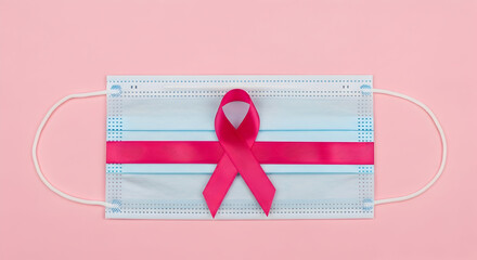 A surgical mask with a pink ribbon on it, symbolizing breast cancer awareness on a pink background