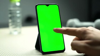 Digital Wellness Engagement with back view of fitness woman using green screen smart phone at home preparing for workout doing a tap on mobile while resting during training distortion, overlay - Powered by Adobe