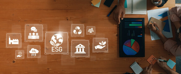 A diverse team collaborates on sustainable strategies using ESG icons and visual data analysis in an engaging workspace, fostering innovation and responsible growth. Trope