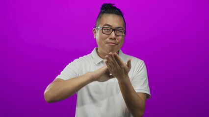 Young chinese man with glasses showing pinching fingers and visible hands in a bright purple studio...