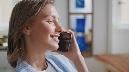 Carefree girl talking smartphone in sunny kitchen. Closeup happy lady end call