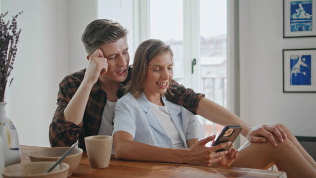 Smiling couple using cellphone indoors. Sweethearts enjoying moment together