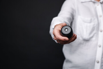 Young woman with hidden spy camera on black background, closeup. Space for text