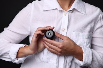 Young woman with hidden spy camera in her pocket on black background, closeup