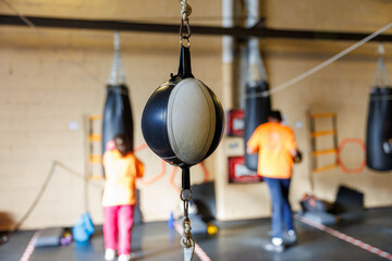 Speed bag hanging in boxing gym, people training