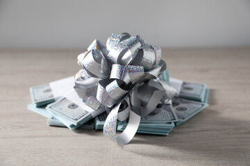 Dollar banknotes with bow on light wooden background, closeup