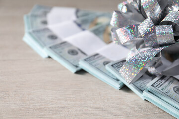 Dollar banknotes with bow on light wooden background, closeup