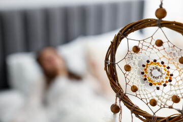 Beautiful dream catcher and woman sleeping on bed at home, selective focus